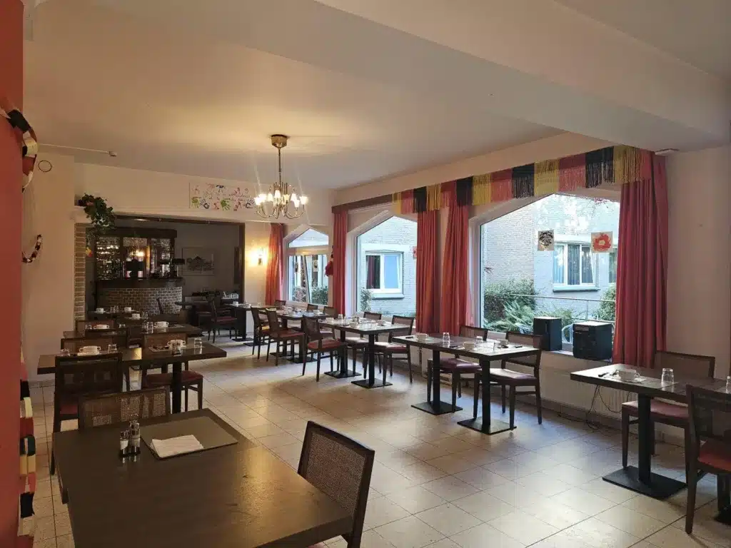 Restaurant avec tables dressées et grandes fenêtres sur le jardin, maison de repos Home Castel à Jette